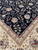 Corner detail where the black floral field meets the beige main border and burgundy stripes