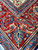 Brick red main border with scrolling vines, blue guard stripes and rosette floral motifs