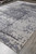Large 10x14 gray modern rug laid flat in the Freeport showroom beside stacked inventory