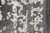 Close-up of ivory and pale blue-gray damask scrollwork floating across a striated charcoal wool and silk pile
