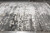 Modern wool and silk area rug displayed flat on gray tile showing ivory pattern dissolving into charcoal field
