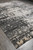 Large 10x14 contemporary hand-knotted rug photographed at an angle on tile, ivory motifs fading into dark gray
