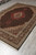 6'8" x 10' Tabriz rug photographed from the corner, showing ivory spandrels and dense black border