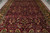Angled view of burgundy field filled with gold palmettes, serrated leaves and scrolling ivory vines