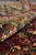 Rolled edge revealing thick wool pile depth, olive border palmettes and deep maroon field
