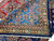 Border corner showing silky wool pile, rosette guard band and crisp knot definition on blue ground