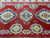 Geometric octagonal medallions in gold and indigo scattered across the red field of this Kazak