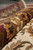 Rolled hand-knotted Indian rug showing pile depth, gold leafwork and maroon border colors