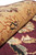 10x14 wool rug rolled to show dense fine pile in gold and maroon