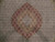 Close-up of layered coral, apricot and gold medallion framed by sage green scalloped outline