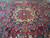 Close view of the 8 lobed ivory medallion surrounded by teal blue and crimson tribal foliage