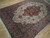 Angled view showing dense floral vinework, olive spandrels and salmon border of this wool and silk rug