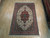 6'5" x 9'10" Persian Tabriz rug shown full length on light hardwood showroom floor