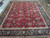 11x15 oversize Persian rug seen from above, red field framed by navy and ivory borders