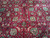 Detail of hand-knotted wool pile with green leaves, pink blossoms and ivory arabesque vines on red