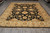 Overhead view of hand-knotted Peshawar rug showing ivory guard stripes around a dense black floral field