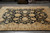9 x 12 Chobi Ziegler rug laid on grey showroom tile with rolled rugs behind