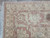 Corner detail of terracotta main border with cream palmettes, sage accents and white cotton fringe