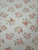 Ivory field close-up with scattered pink roses and sage leaves, faint storage fold lines visible