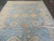 Large 9x12 Oushak area rug photographed lengthwise, showing ivory guard stripes and blue field