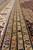 Layered gold, grey and ivory guard borders with small rosettes and paisley motifs in wool