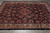Wide view of hand-knotted wool pile, black ground and rose red floral lattice across the field
