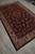 7x11 Persian Sarouk area rug on grey tile, showing ivory border and ink black center field