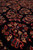 Macro of madder red petals, cream leaves and blue accents on the inky black wool pile