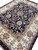 Perspective shot highlighting scrolling vines, palmettes and rust rosettes across the black field and cream border