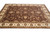 9 x 12 hand-knotted wool rug seen from the side, brown field with wide ivory border