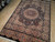 Angled showroom view of the 6x9 black Oriental rug showing medallion, border cartouches and pile texture