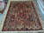 Hand-knotted Bakhtiar rug laid flat on showroom floor showing ivory border and multicolored garden panel field