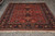 Full length view of rust and navy all over floral rug with thick ivory fringe