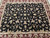 Full field photographed from one end, black ground with symmetrical floral repeat and burgundy borders