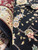Close-up of folded pile showing silk highlights, salmon rosettes and dense wool knots on black ground
