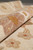 Rolled edge of the rug revealing dense wool pile and mauve floral rosette detail