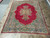 Full view of the 8'8" x 11'7" Kerman rug with open red field and ivory corner scrolls