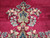 Pendant close-up of sky blue blossoms and ivory leaves resting on lustrous pomegranate red wool