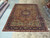 Living room size Persian rug laid flat in the Freeport showroom, showing full medallion and ivory corners