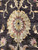 Single large gold palmette with burgundy and ivory petals resting on near black wool pile