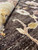 Pile close-up showing hand-knotted wool texture, soft sheen and the folded edge of the rug