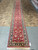 Warehouse view of the deep red wool and silk runner showing ivory guard stripes and fringe