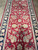 Detail of ivory palmettes, pink roses and sage green leaves on the deep red field