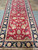 Close view of the traditional all-over floral vine pattern and black border of this runner