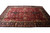 Hand-knotted Indian wool rug seen from the side, navy main border framing dense red field