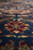 Angled macro of a red and ivory palmette blooming across the dark navy wool field