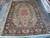 9'9" x 13'7" Persian Tabriz rug displayed flat on showroom floor beside rolled rugs