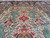 Teal cloud cartouches and pink pictorial panels frame the ivory field above the central medallion