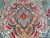 Macro detail of hand-knotted wool pile showing rose blossoms and fern leaves inside the medallion