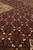 Low angle close-up of dense herati knotting with cream flower heads on dark red ground
